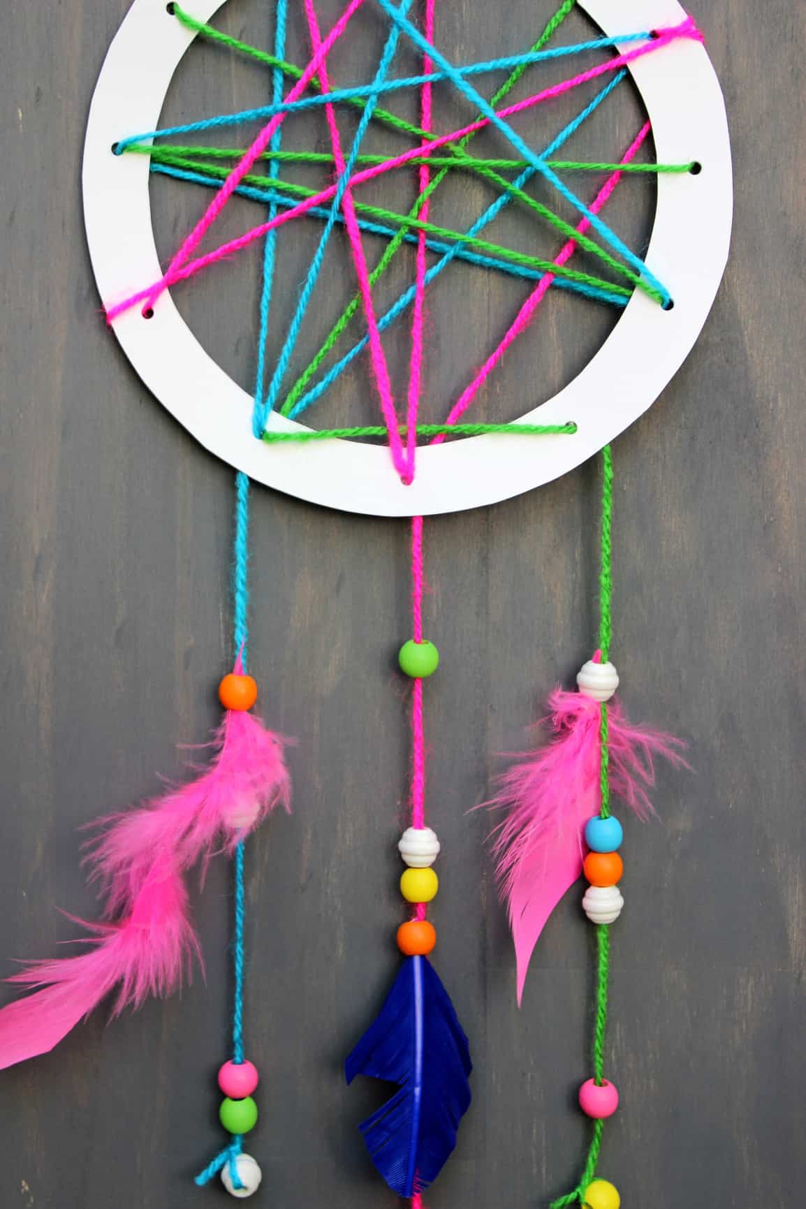 image shows a dreamcatcher made from colorful yarn, feathers, and beads.