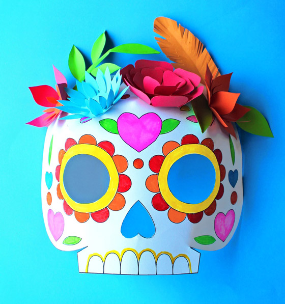 image shows a cardstock skull mask, colored with markers and decorated with colorful paper flowers.