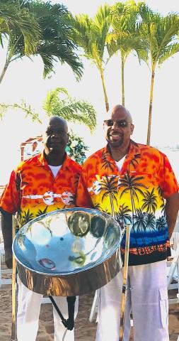 band wearing island shirts standing next to steel drums